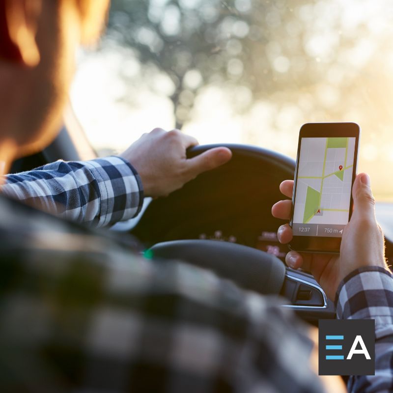 A person behind the wheel of a car looking at a navigation app