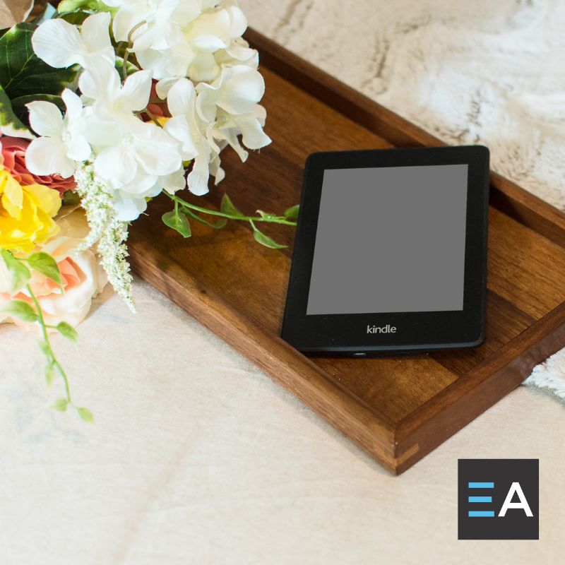 An e-reader lying on a tray next to flowers